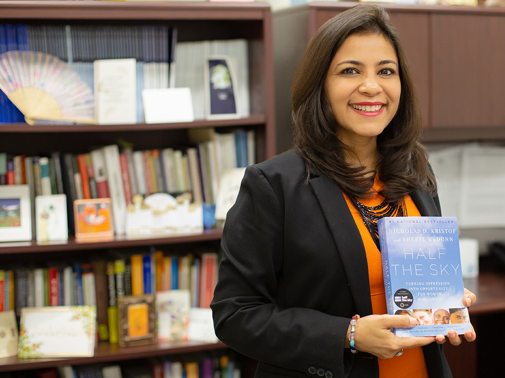 Woman holding a book in front of a book shelf