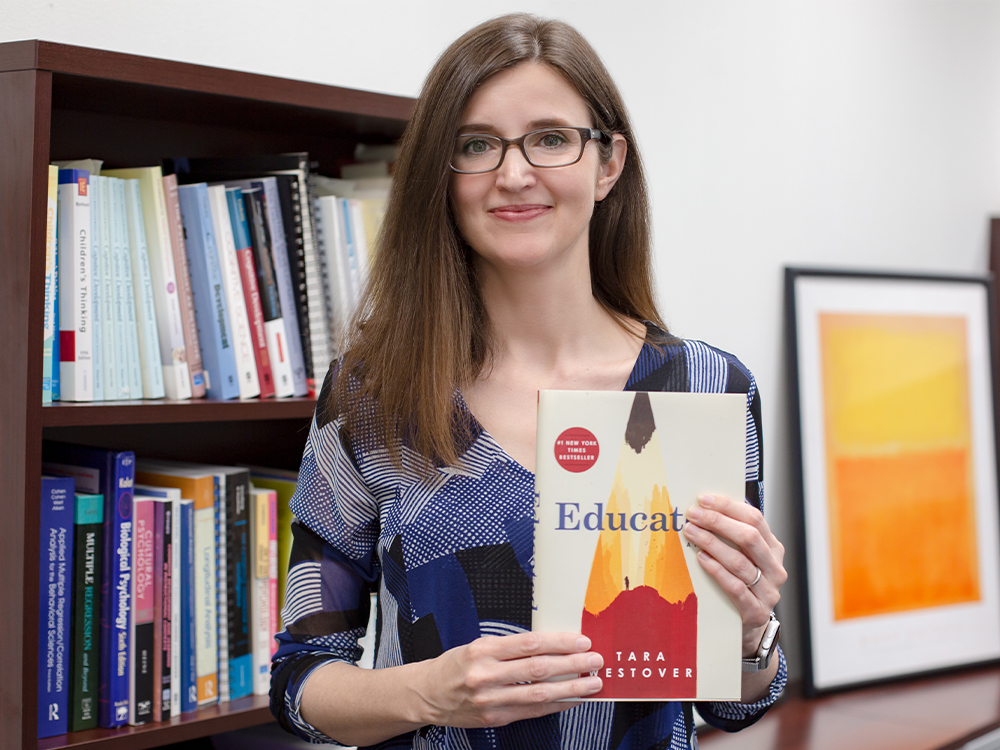 Woman holding book in front of bookshelf